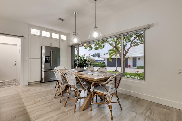 dining area featuring light hardwood / wood-style flooring and a barn door