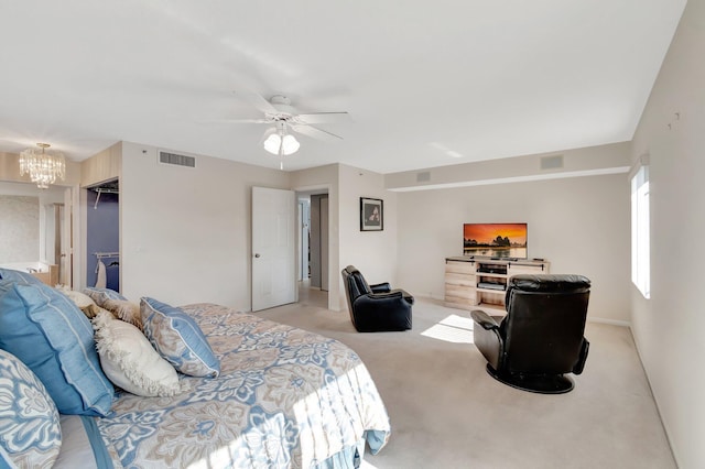 bedroom featuring ceiling fan with notable chandelier, a walk in closet, light colored carpet, and a closet