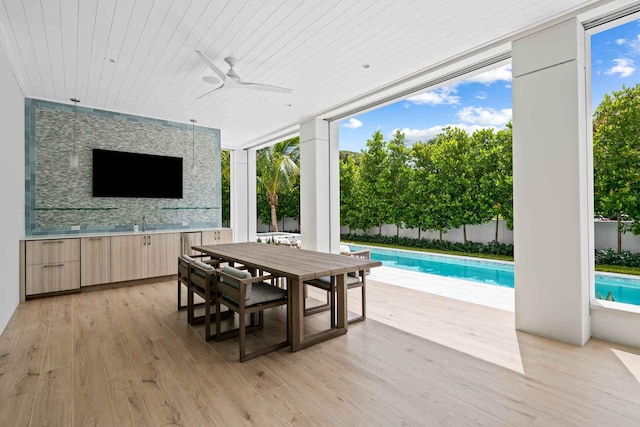 wooden terrace featuring ceiling fan and a fenced in pool