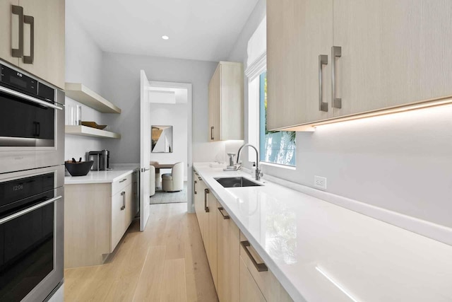 kitchen with sink, light hardwood / wood-style floors, light brown cabinetry, and double oven