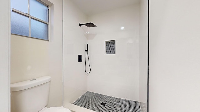 bathroom featuring toilet and a tile shower