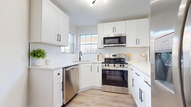 kitchen featuring appliances with stainless steel finishes, light hardwood / wood-style floors, white cabinetry, and sink