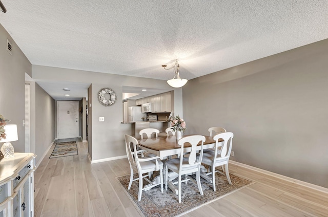 dining room with a textured ceiling and light wood-type flooring