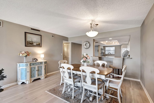 dining room featuring a textured ceiling and light hardwood / wood-style flooring