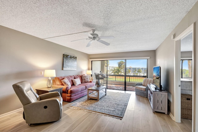 living room with a textured ceiling, light hardwood / wood-style flooring, and ceiling fan