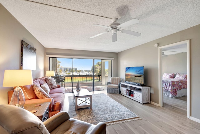 living room featuring ceiling fan, a textured ceiling, and light hardwood / wood-style floors