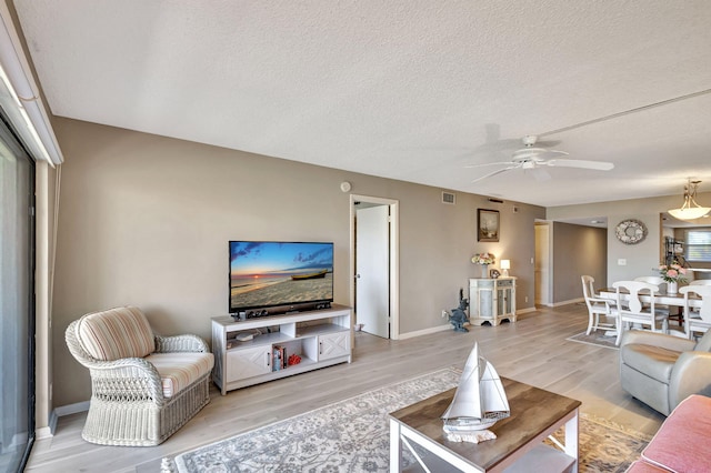 living room with ceiling fan, wood-type flooring, and a textured ceiling