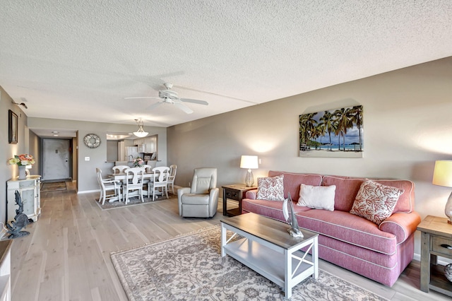 living room with a textured ceiling, wood-type flooring, and ceiling fan