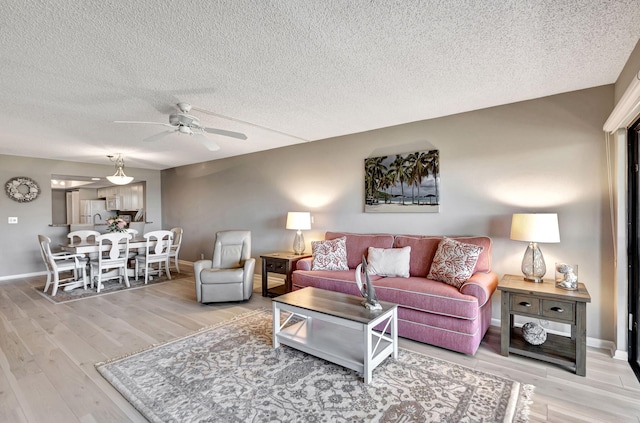 living room featuring ceiling fan, hardwood / wood-style floors, and a textured ceiling