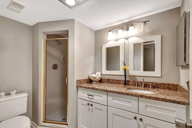 bathroom featuring vanity, toilet, and a shower with shower door