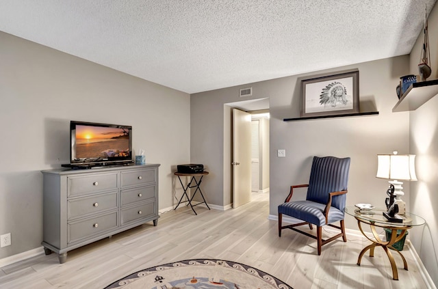 sitting room featuring light hardwood / wood-style floors and a textured ceiling