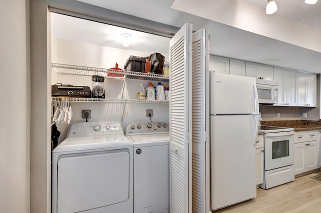 clothes washing area featuring washer and clothes dryer and light wood-type flooring