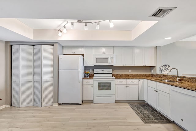 kitchen featuring sink, white appliances, white cabinetry, dark stone countertops, and a raised ceiling