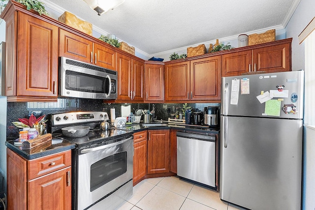 kitchen featuring ornamental molding, a textured ceiling, light tile patterned floors, and appliances with stainless steel finishes