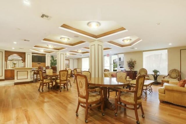 dining area with decorative columns, light hardwood / wood-style floors, and coffered ceiling