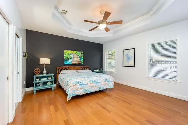 bedroom featuring hardwood / wood-style flooring, ceiling fan, crown molding, and a raised ceiling