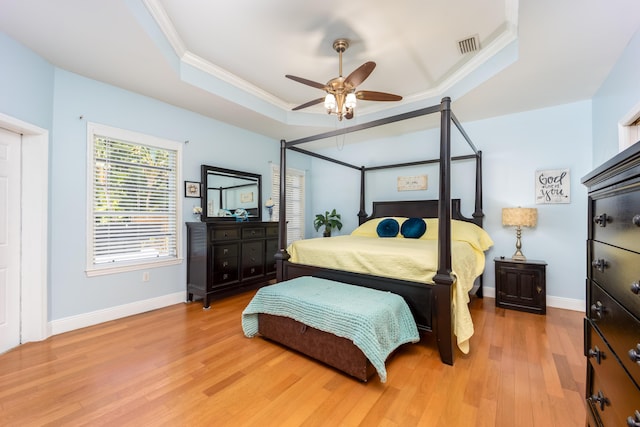 bedroom featuring ceiling fan, crown molding, a tray ceiling, and light hardwood / wood-style floors