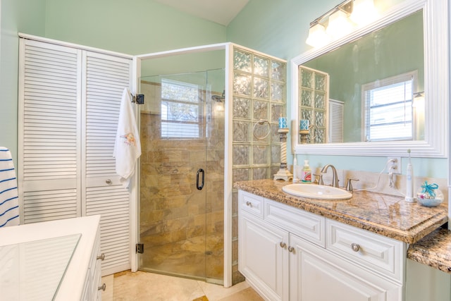 bathroom with a shower with shower door, vanity, and tile patterned floors