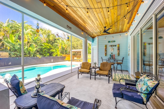 sunroom / solarium featuring ceiling fan, a wealth of natural light, and wood ceiling