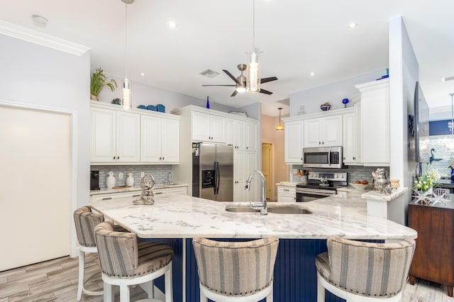 kitchen with decorative light fixtures, sink, stainless steel appliances, and white cabinetry