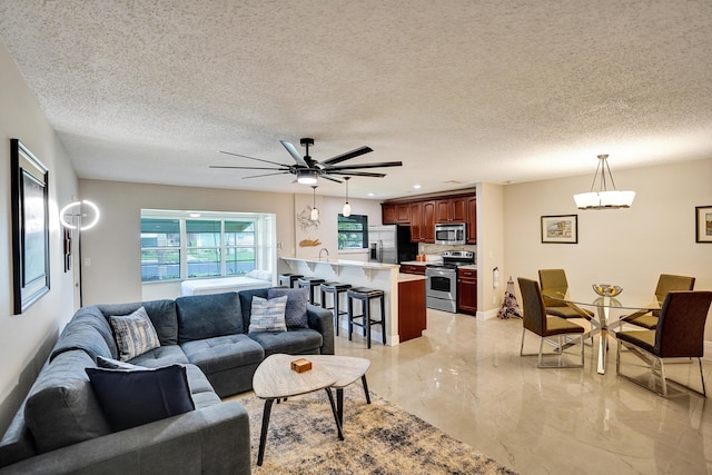 living room featuring ceiling fan and a textured ceiling