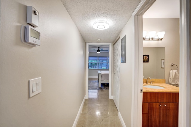 corridor featuring sink and a textured ceiling