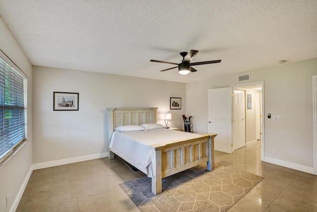 bedroom with a textured ceiling, ceiling fan, and tile patterned floors