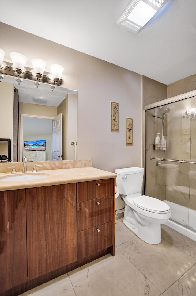 bathroom featuring toilet, a shower with shower door, and vanity