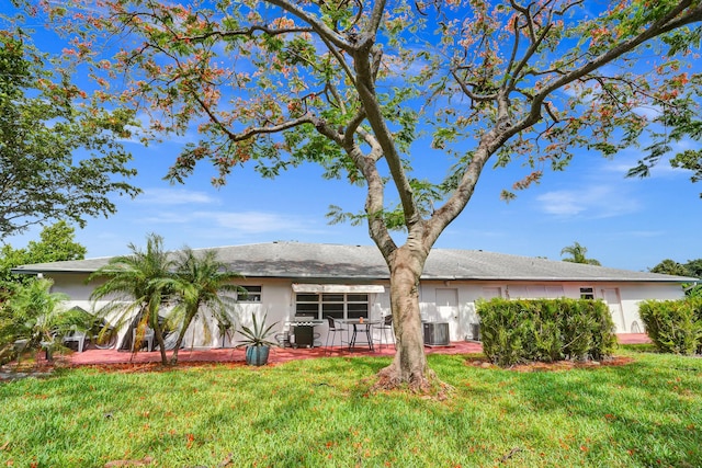 back of property with central air condition unit and a lawn