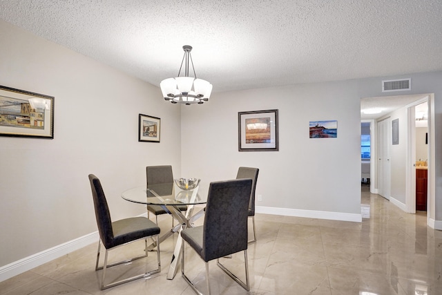 dining space with a textured ceiling and a notable chandelier