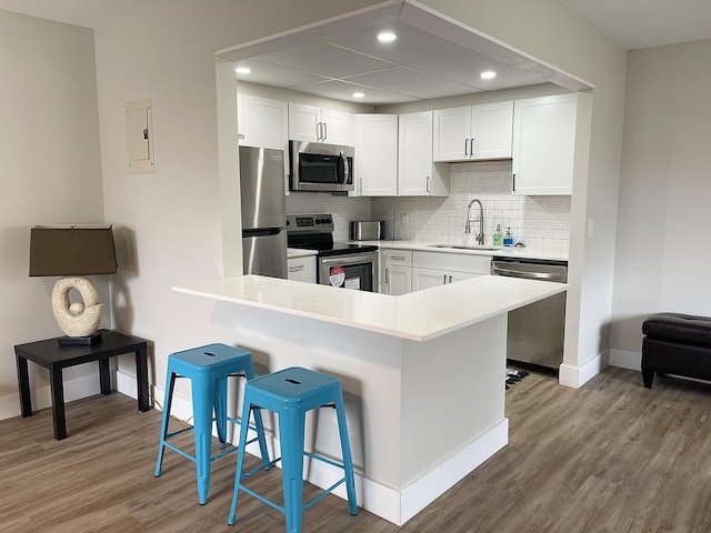 kitchen featuring white cabinets, a kitchen bar, stainless steel appliances, tasteful backsplash, and sink