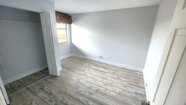 unfurnished bedroom featuring a textured ceiling, light hardwood / wood-style floors, and a closet