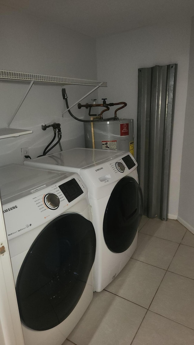 washroom featuring washing machine and dryer, water heater, and light tile patterned floors