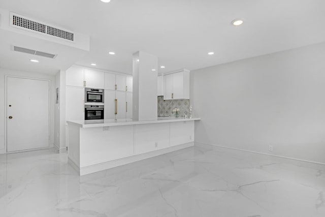 kitchen with white cabinets, kitchen peninsula, and backsplash