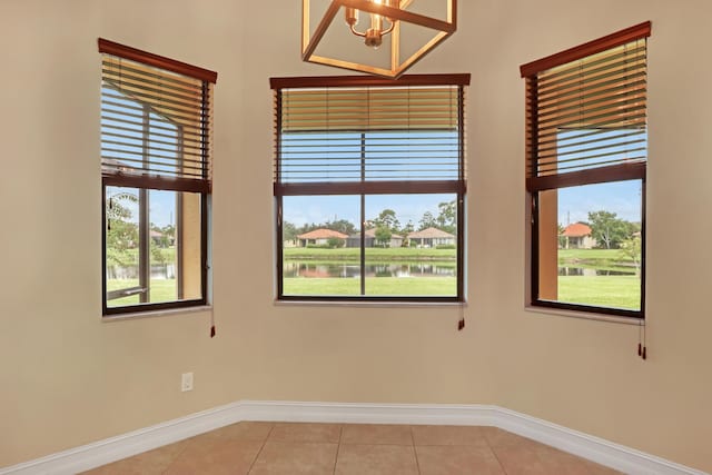 unfurnished room featuring a water view and light tile patterned flooring