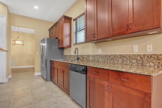 kitchen featuring appliances with stainless steel finishes, sink, hanging light fixtures, a notable chandelier, and light stone counters