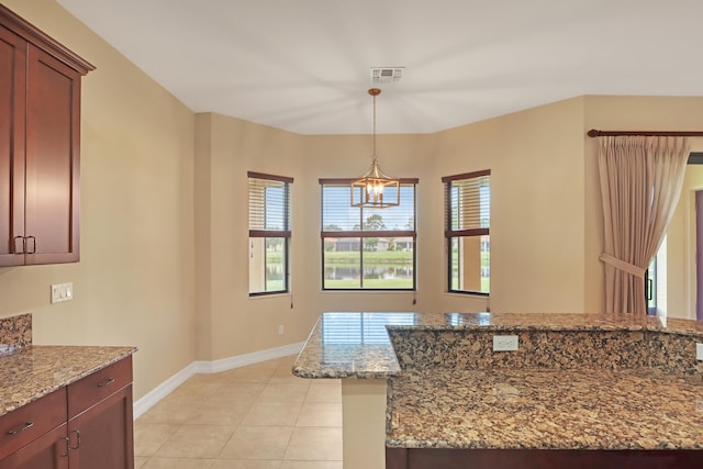 kitchen featuring an inviting chandelier, light tile patterned floors, pendant lighting, and light stone counters