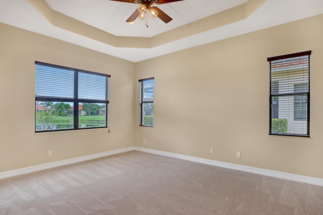 unfurnished room with light carpet, ceiling fan, and a raised ceiling