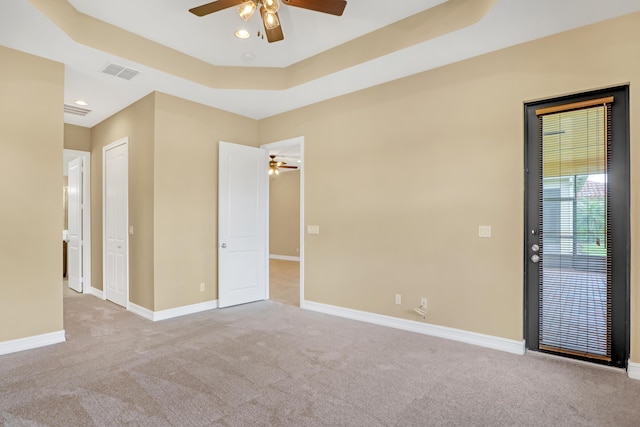 carpeted spare room featuring ceiling fan and a tray ceiling