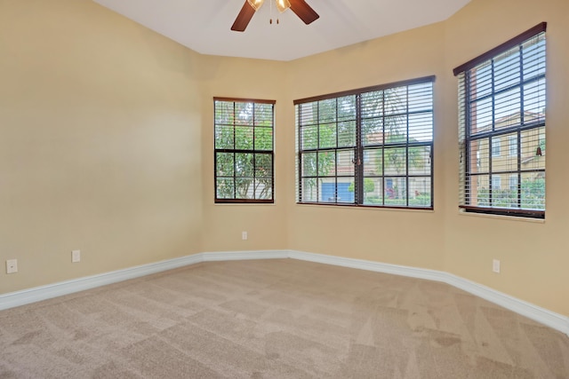 unfurnished room featuring ceiling fan, light colored carpet, and plenty of natural light