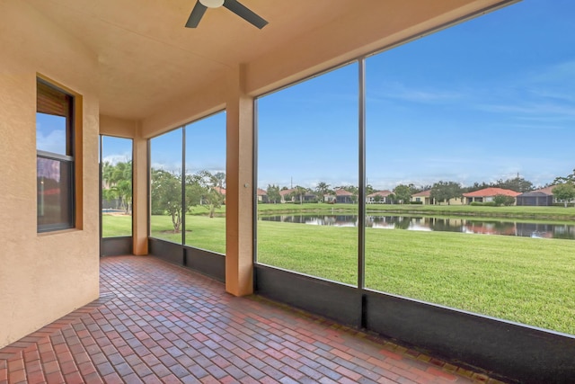 unfurnished sunroom with ceiling fan and a water view