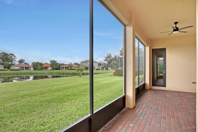 unfurnished sunroom featuring ceiling fan and a water view