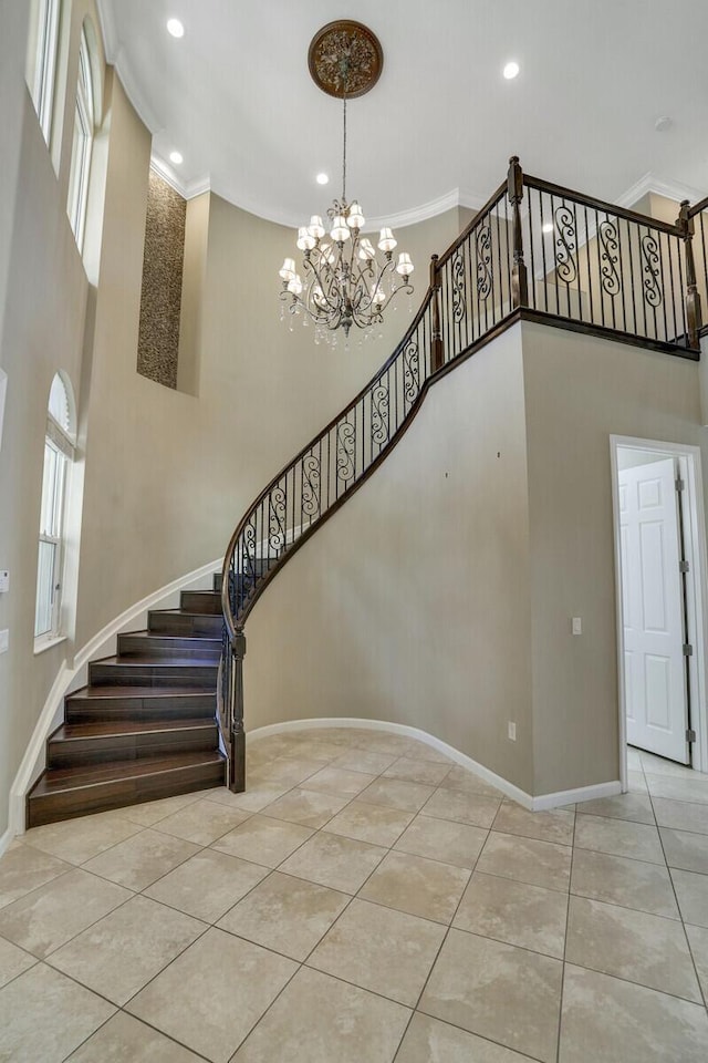 stairs featuring a high ceiling, ornamental molding, tile patterned floors, and an inviting chandelier