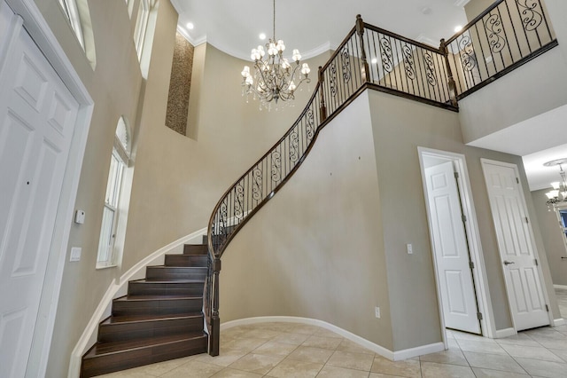 staircase featuring ornamental molding, tile patterned floors, a chandelier, and a high ceiling