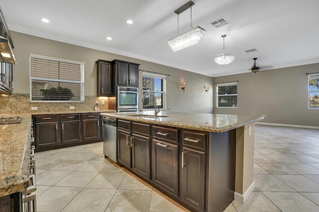 kitchen with sink, decorative light fixtures, light tile patterned floors, stainless steel appliances, and a kitchen island with sink