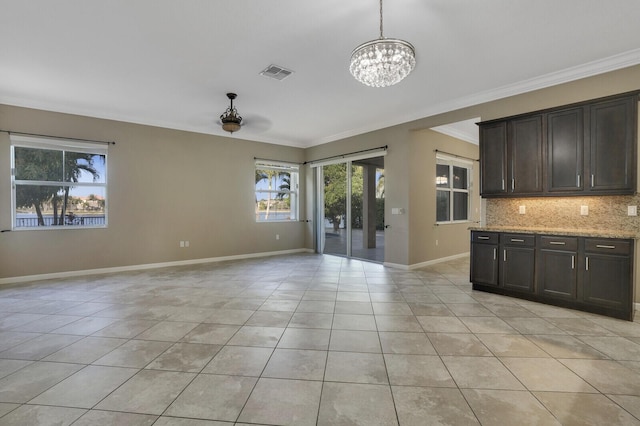 unfurnished living room featuring crown molding, a notable chandelier, and light tile patterned floors