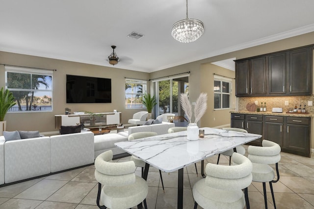 tiled dining space featuring ornamental molding and a notable chandelier