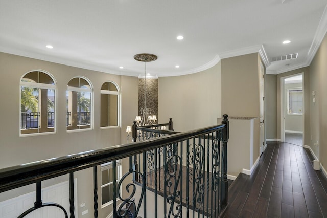 hallway with an inviting chandelier, crown molding, and dark hardwood / wood-style flooring