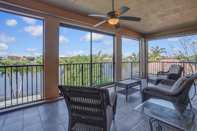 sunroom / solarium with a wealth of natural light, ceiling fan, and a water view