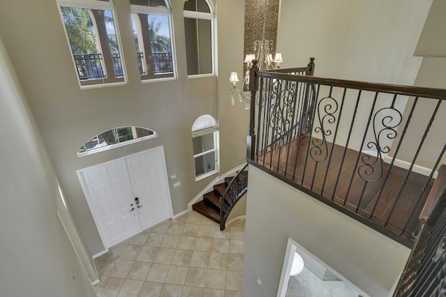 tiled entryway with a towering ceiling and a chandelier